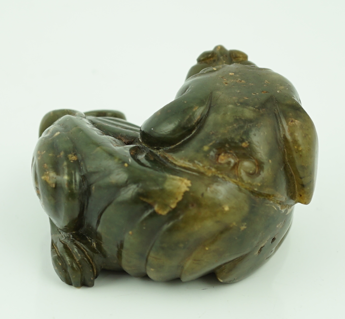 A Chinese Ming green soapstone figure of a recumbent lion-dog, 16th/17th century